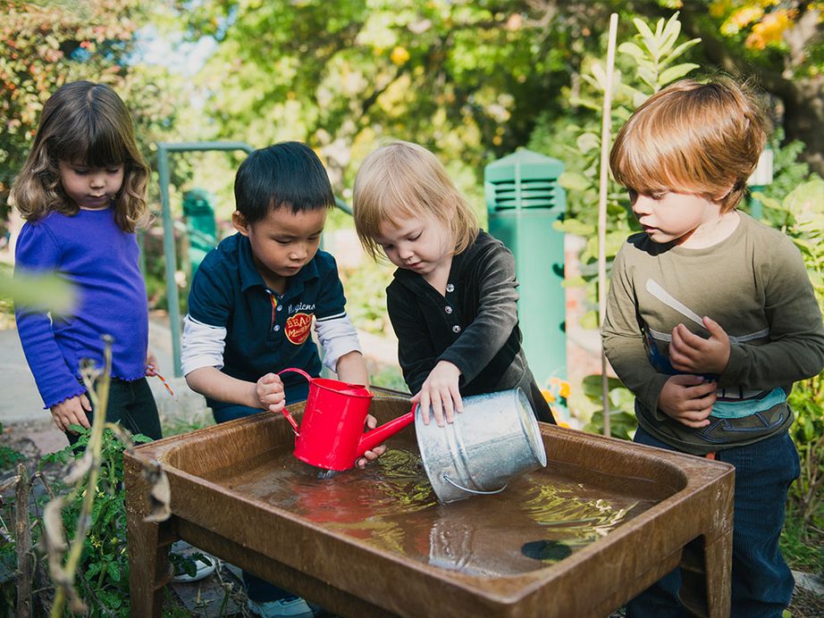 Children with a watering can exploring outdoors